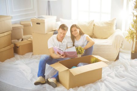 Téléchargez les photos : Heureux jeune couple déballer ou emballer des boîtes et emménager dans une nouvelle maison
. - en image libre de droit