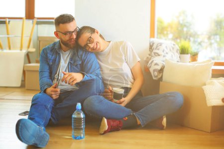 Photo for Happy couple planning decoration when moving home sitting on the floor. - Royalty Free Image