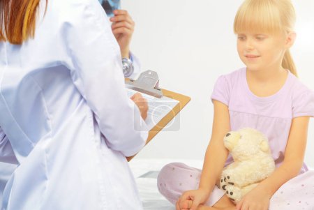 Photo for Female doctor examining child with stethoscope at surgery. - Royalty Free Image