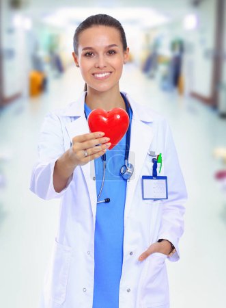 Téléchargez les photos : Médecin féminin positif debout avec stéthoscope et symbole du cœur rouge isolé. Femme médecin
. - en image libre de droit