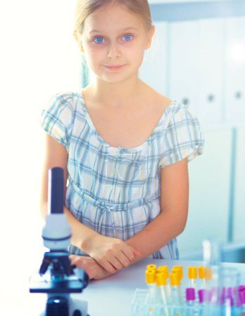 Photo for Schoolgirl looking through microscope in science class - Royalty Free Image