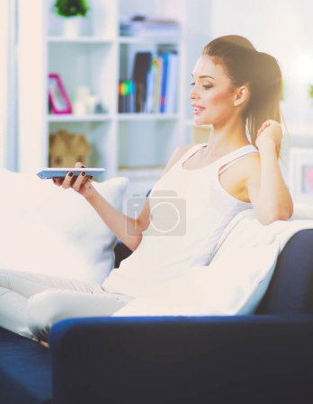 Foto de Mujer bonita en su sala de estar sentada en el sofá enviando mensajes
. - Imagen libre de derechos