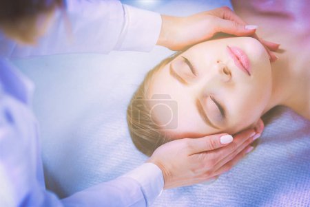 Téléchargez les photos : Jeune femme allongée sur une table de massage, relaxante les yeux fermés. Femme. Salon de spa. - en image libre de droit