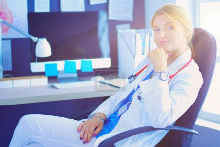 Photo for Portrait of young female doctor sitting at desk in hospital. - Royalty Free Image