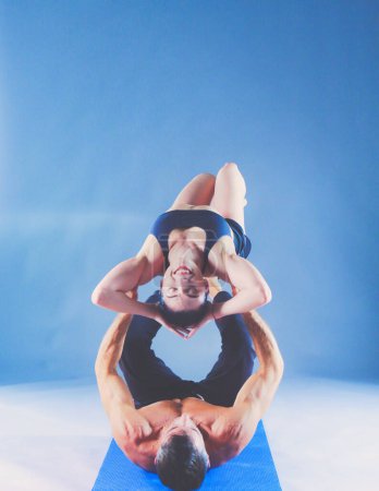 Photo for Young couple practicing acro yoga on mat in studio together. Acroyoga. Couple yoga. Partner yoga - Royalty Free Image