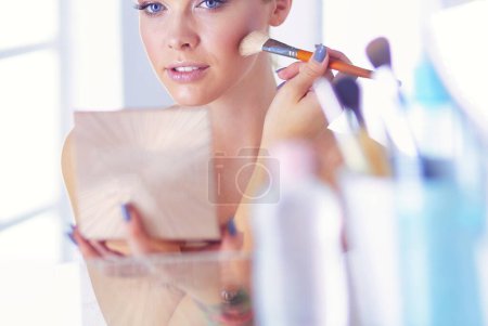Photo for A picture of a young woman applying face powder in the bathroom. - Royalty Free Image