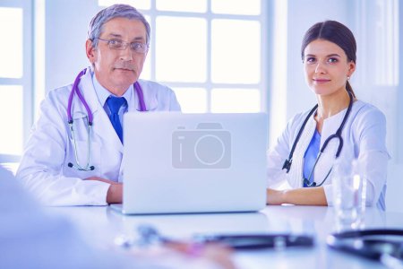 Téléchargez les photos : Équipe médicale sérieuse utilisant un ordinateur portable dans un bureau lumineux - en image libre de droit