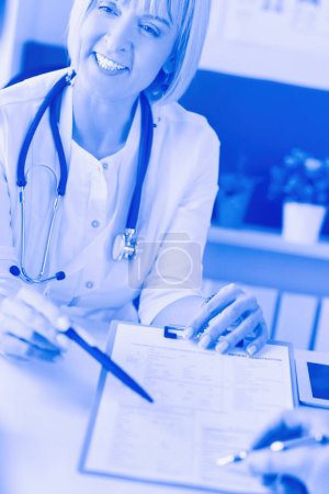 Photo for Doctor and patient examining a file with medical records, she is sitting on a wheelchair. - Royalty Free Image