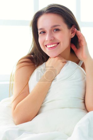 Photo for Pretty woman lying down on her bed at home. - Royalty Free Image