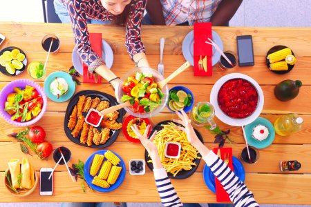 Téléchargez les photos : Vue du dessus du groupe de personnes qui dînent ensemble tout en étant assis à une table en bois. De la nourriture sur la table. Les gens mangent fast food. - en image libre de droit