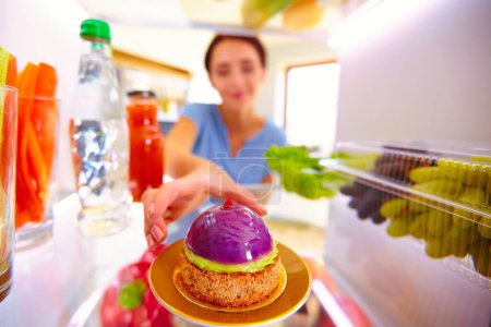 Photo for Portrait of female standing near open fridge full of healthy food, vegetables and fruits. Portrait of female. - Royalty Free Image