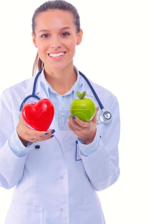 Téléchargez les photos : Belle femme médecin souriante tenant coeur rouge et pomme verte. Femme médecin - en image libre de droit