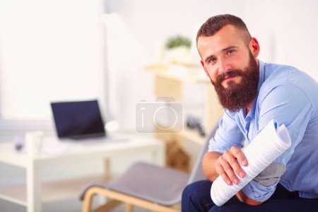Téléchargez les photos : Jeune homme d'affaires assis sur une chaise dans le bureau. - en image libre de droit
