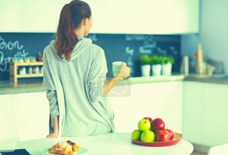 Photo for Happy woman drinking tea in the kitchen at home. - Royalty Free Image