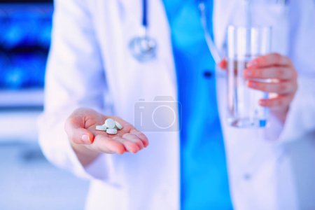 Foto de Primer plano de las manos de los médicos sosteniendo pastillas y vaso de agua - Imagen libre de derechos
