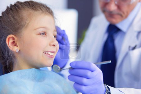 Kleines Mädchen sitzt in der Zahnarztpraxis.