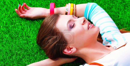 Photo for Beautiful young woman lying on the green grass. - Royalty Free Image