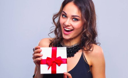 Foto de Mujer joven sonrisa feliz celebrar caja de regalo en las manos, aislado sobre fondo gris
. - Imagen libre de derechos