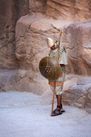 Téléchargez les photos : Petra, Jordanie - 3 novembre 2022 : Homme habillé comme une ancienne garde nabatéenne, dormant à l'entrée du site archéologique - en image libre de droit