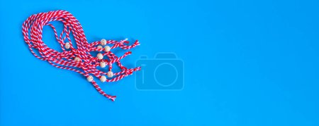 Photo for Bulgarian symbol of spring, many white and red martenitsa bracelets on blue banner background - Royalty Free Image