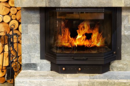 Cheminée en pierre avec des flammes de feu ardent, Maison confortable de style rustique en hiver