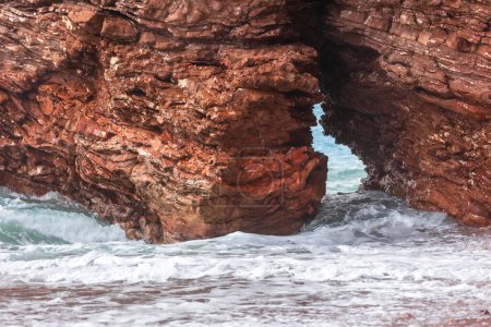 Foto de Playa salvaje Crvena Glavica en Montenegro. Rocas rojas arco costero y olas de agua - Imagen libre de derechos