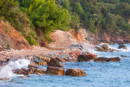 Foto de Playa salvaje Crvena Glavica en Montenegro. Rocas rojas costa y olas de agua - Imagen libre de derechos