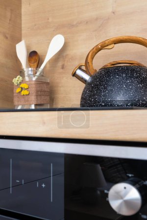 Téléchargez les photos : Bouilloire vintage en granit sur le dessus de la cuisinière et ensemble de spatules de cuisine en pot en verre - en image libre de droit