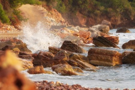 Foto de Playa salvaje Crvena Glavica en Montenegro. Rocas rojas costa y olas de agua - Imagen libre de derechos