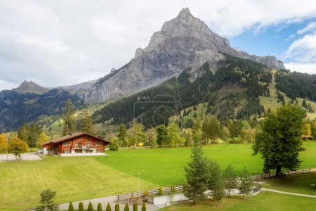 Wooden chalet in Kandersteg village, Canton Bern, Switzerland, Europe, Autumn trees and mountains panorama