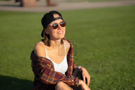 Foto de Mujer joven sonriente relajándose en la hierba en el parque público - Imagen libre de derechos