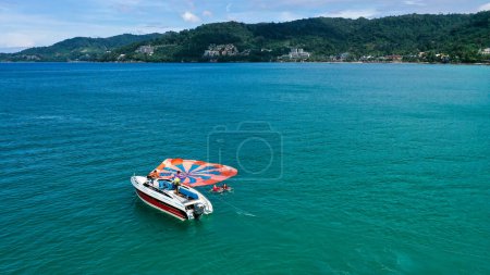 Photo for View from above of clear sea water with staff and tourists heading to boat after finished parasailing. - Royalty Free Image