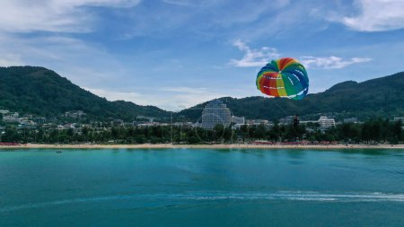 Photo for Tourist is enjoying a parasailing ride at Patong beach in Phuket of Thailand. Water sport activity. Thailand extreme Sports. - Royalty Free Image
