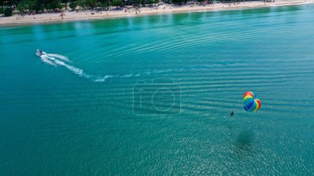 Photo for View from above of a tourist play parasailing with a boat towing it. - Royalty Free Image