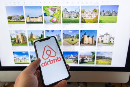 Téléchargez les photos : Paris, France - 30 novembre 2023 : Smartphone portatif féminin avec application Airbnb. Airbnb est un marché en ligne et un service d'accueil, permettant aux gens de louer ou louer un hébergement à court terme - en image libre de droit