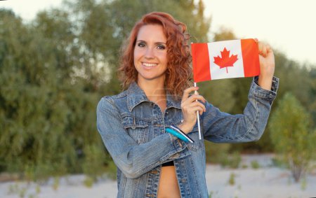 Foto de Mujer joven sonriente con bandera de Canadá en el fondo de la naturaleza. - Imagen libre de derechos