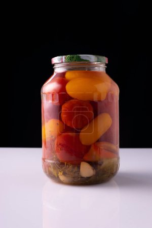 canned vegetables in a jar on a white table and black background.