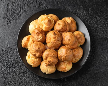 Photo for Savoury profiteroles stuffed with Molten cheddar cheese sauce, party food concept. - Royalty Free Image