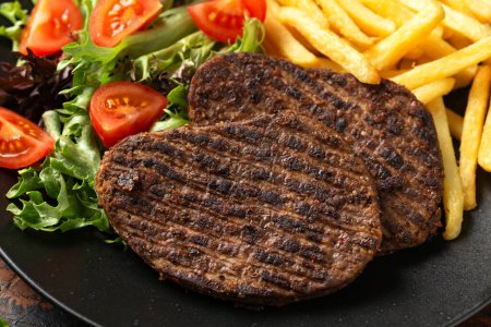 Téléchargez les photos : Steaks végétariens poivrés servis avec frites et salade. - en image libre de droit