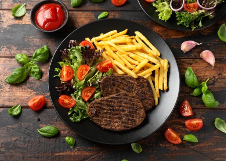 Steaks végétariens poivrés servis avec frites et salade.