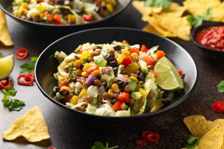 Téléchargez les photos : Salade mexicaine de haricots noirs, lentilles, maïs, tomate et laitue avec une salsa et des chips de tortilla. - en image libre de droit