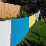A washing line with colourful pegs and different colour towels hanging to dry in the sun