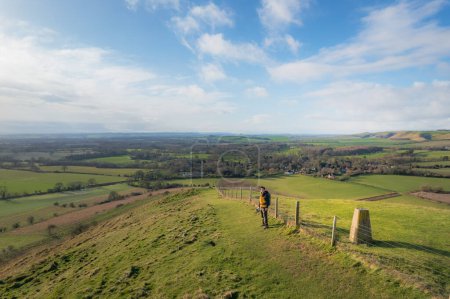 Photo for Backpacker walking on footpath, beautiful hill and landscape near Pewsey, South of England, United Kingdom, winter daytime - Royalty Free Image