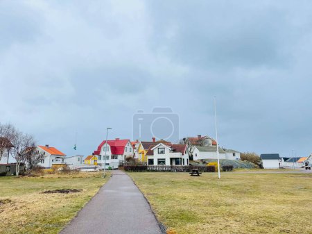 Photo for Vrango, Southern Gothenburg Archipelago, Sweden - 8 April 2022: A view of a village with red wooden houses on Vrango, Southern Gothenburg Archipelago, Cloudy sky. - Royalty Free Image