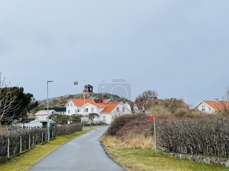 Photo for Vrango, Southern Gothenburg Archipelago, Sweden - 8 April 2022: A view of a village with white wooden houses on Vrango, Southern Gothenburg Archipelago, Cloudy sky. - Royalty Free Image