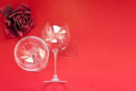 Photo for Two Empty wine glasses lies on a red background. Flat lay, top view, copy space ,minimal valentines day romance concept. Horizontal photo - Royalty Free Image