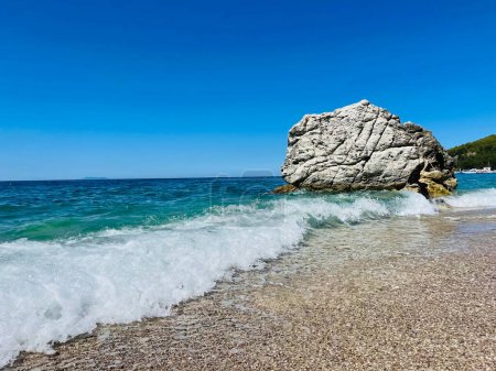 Photo for Rocky beach and crystal turquoise water of Ionian Sea in Albania. Calm and relaxing view with flowers. summer holidays concept. Copy space. - Royalty Free Image