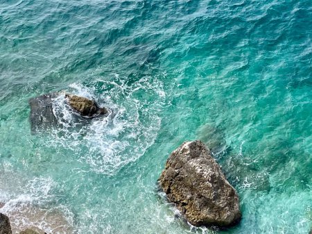 Playa rocosa y agua cristalina turquesa del mar Jónico en Albania. Calma y relajante vista con flores. vacaciones de verano concepto de fondo. Copiar espacio. Fotografía horizontal. 
