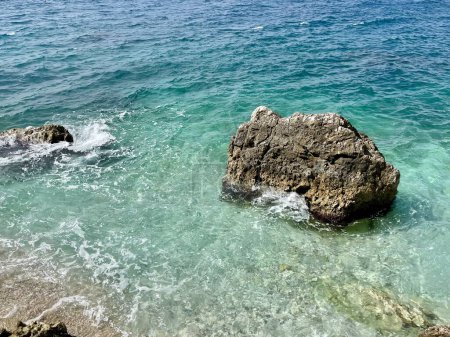 Photo for Rocky beach and crystal turquoise water of Ionian Sea in Albania. Calm and relaxing view with flowers. summer holidays concept background. Copy space. Horizontal photo. - Royalty Free Image