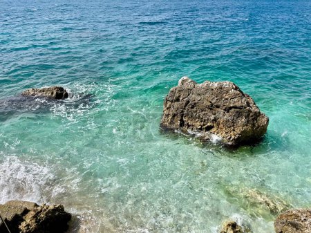 Photo for Rocky beach and crystal turquoise water of Ionian Sea in Albania. Calm and relaxing view with flowers. summer holidays concept background. Copy space. Horizontal photo. - Royalty Free Image